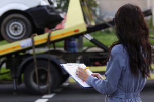 female insurance adjuster writing on notepad inspecting truck cargo