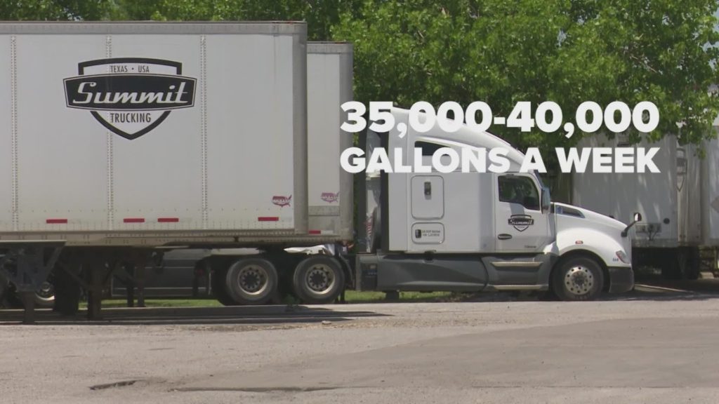 The white semi-truck used to transport goods & sitting at a gas station, needs to fill up with fuel frequently as it uses about 40,000 gallons of gas a week.