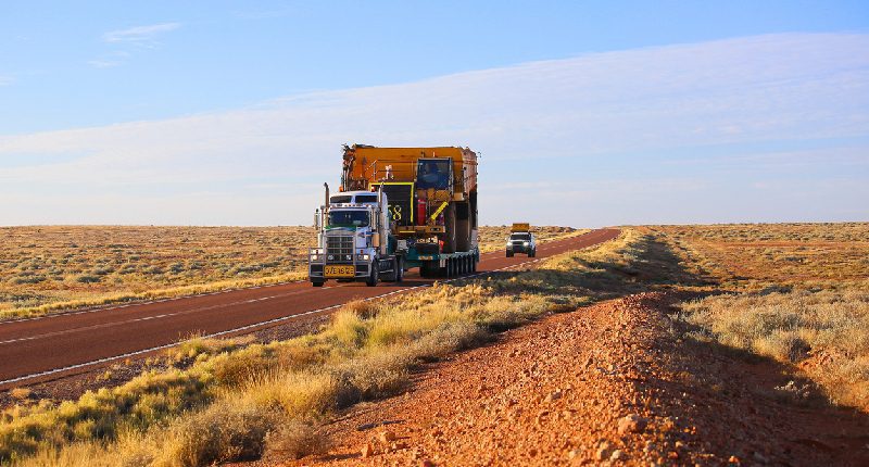 Heavy haul truck and trailer hauling large construction dump truck.