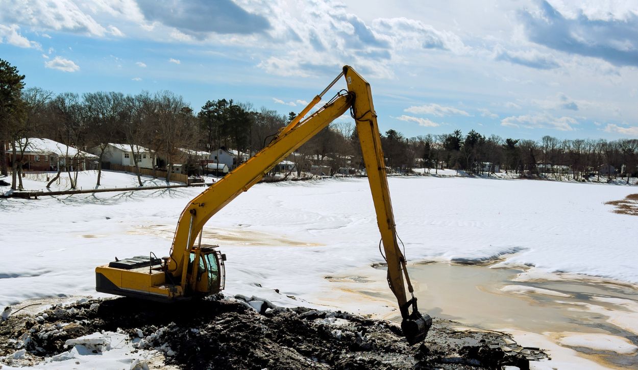 A long-reach excavator cleaning the bottom of a lake in the winter