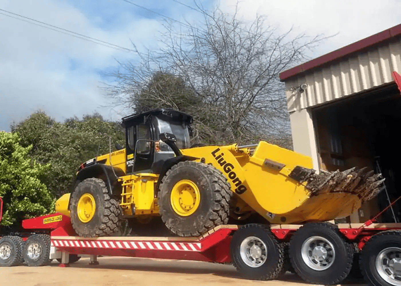 Yellow LiuGong wheel loader on red flatbed trailer.